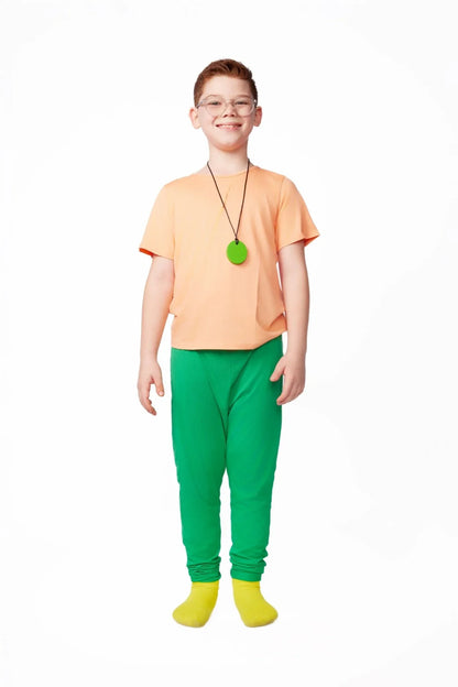 Smiling boy in sensory-friendly orange shirt, green pants, green pendant, and yellow socks