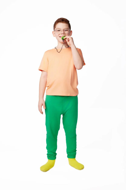 Child wearing sensory-friendly clothing, peach shirt and green pants, with a chewable necklace.