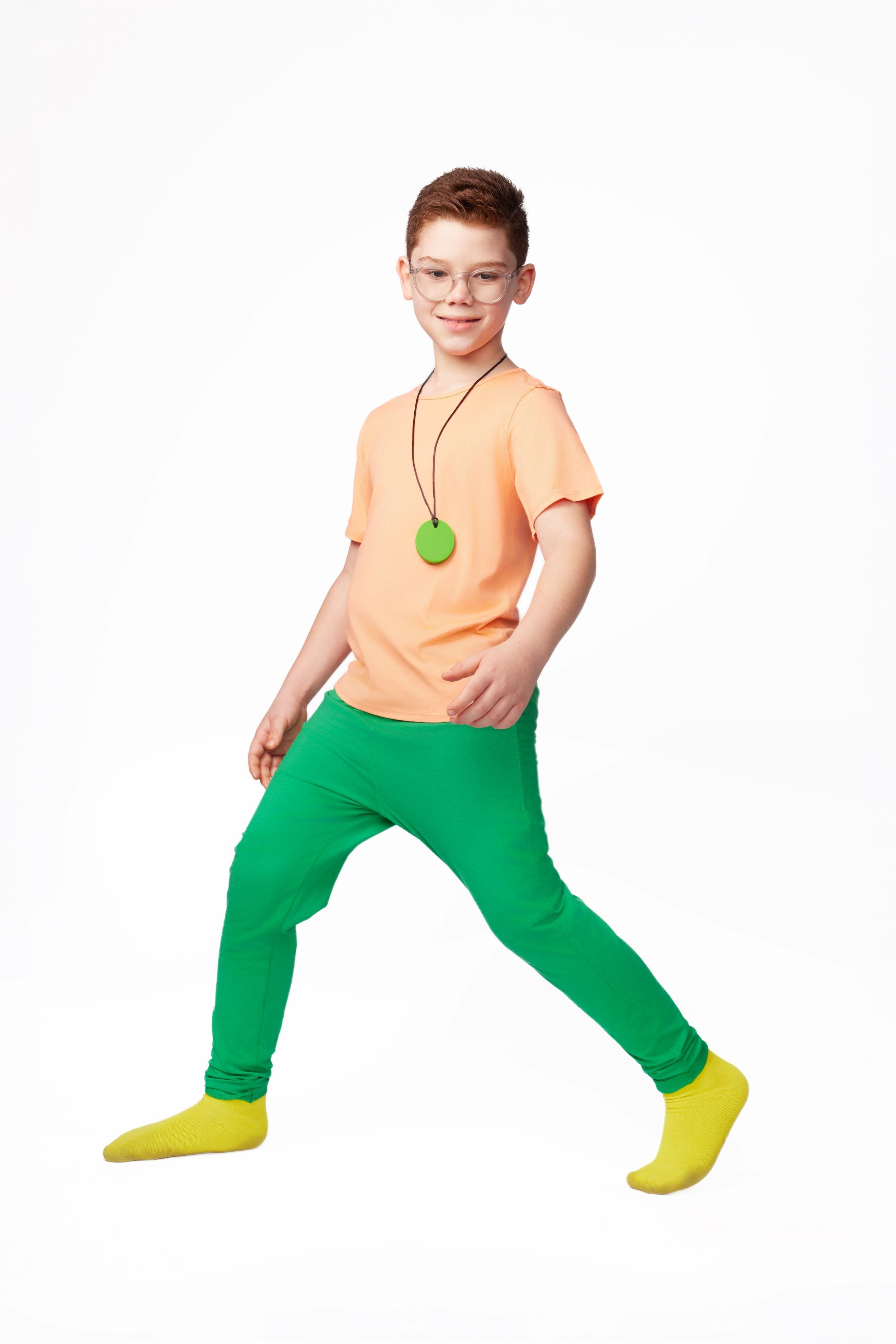 Person wearing a bright orange shirt, green pants, and yellow shoes on a white background
