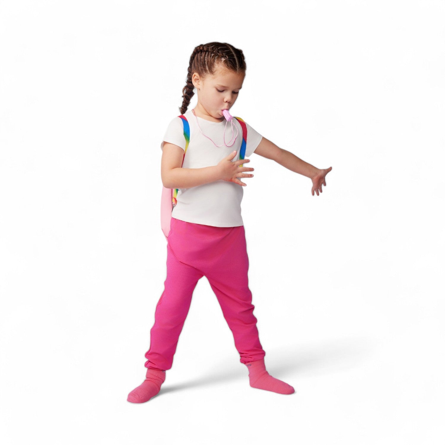 Young girl in pink pants and white shirt with colorful backpack on a white background
