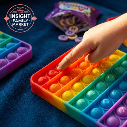 Child's hand pressing rainbow pop it sensory fidget toy with alphabet letters, learning tool on table.