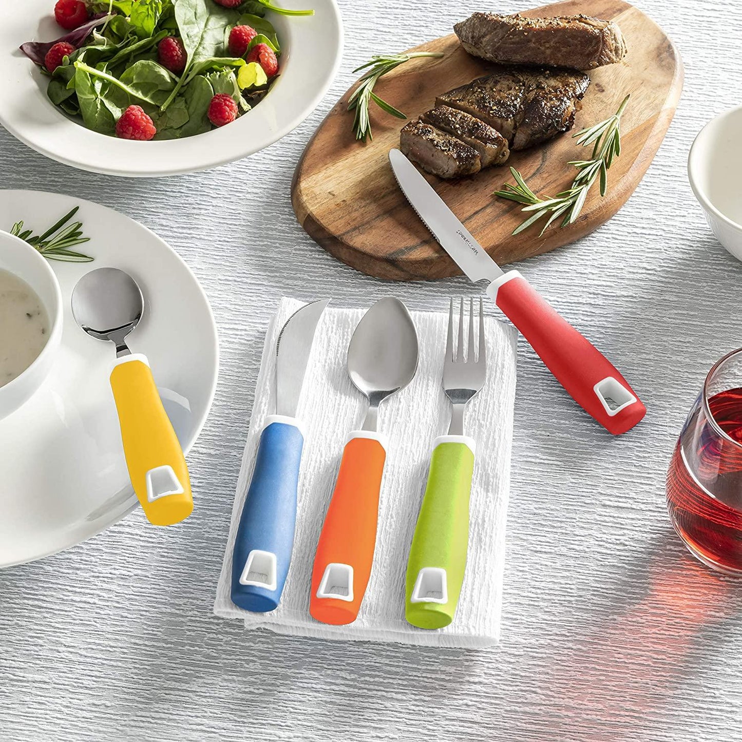 Adaptive utensils with colorful easy-grip handles on table, ideal for sensory-friendly dining.
