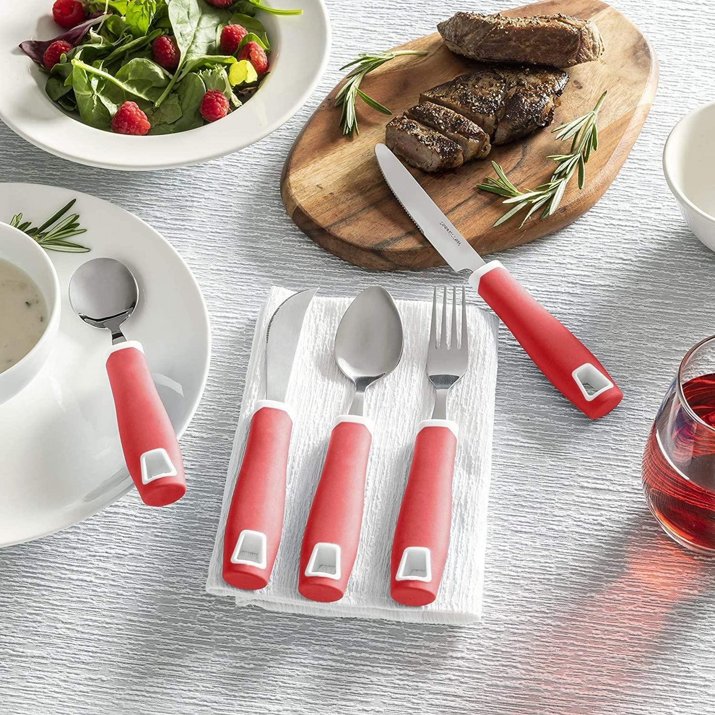 Adaptive red handle utensils set for arthritis on dining table with food