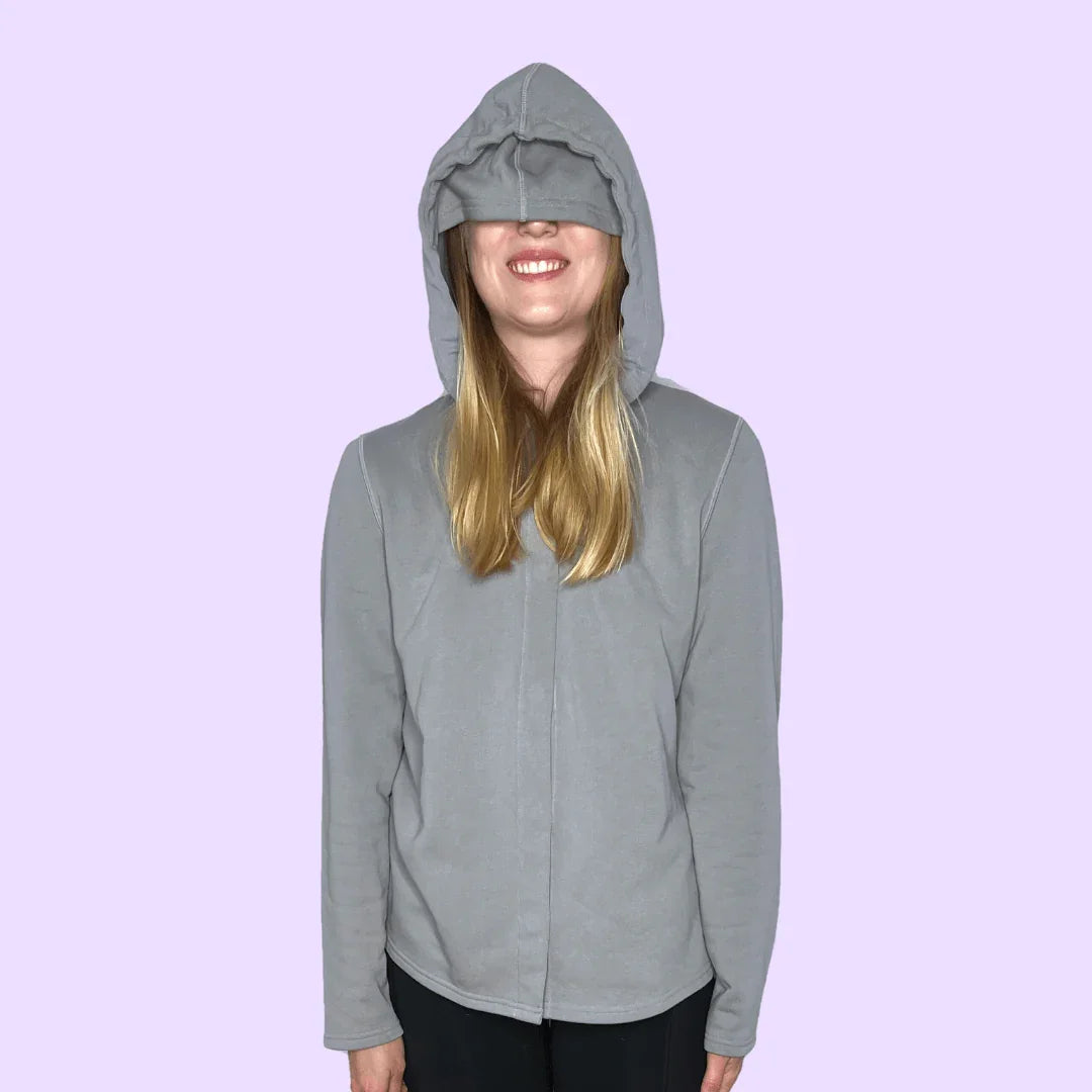 Adult wearing sensory-friendly grey hoodie with oversized hood, lavender background