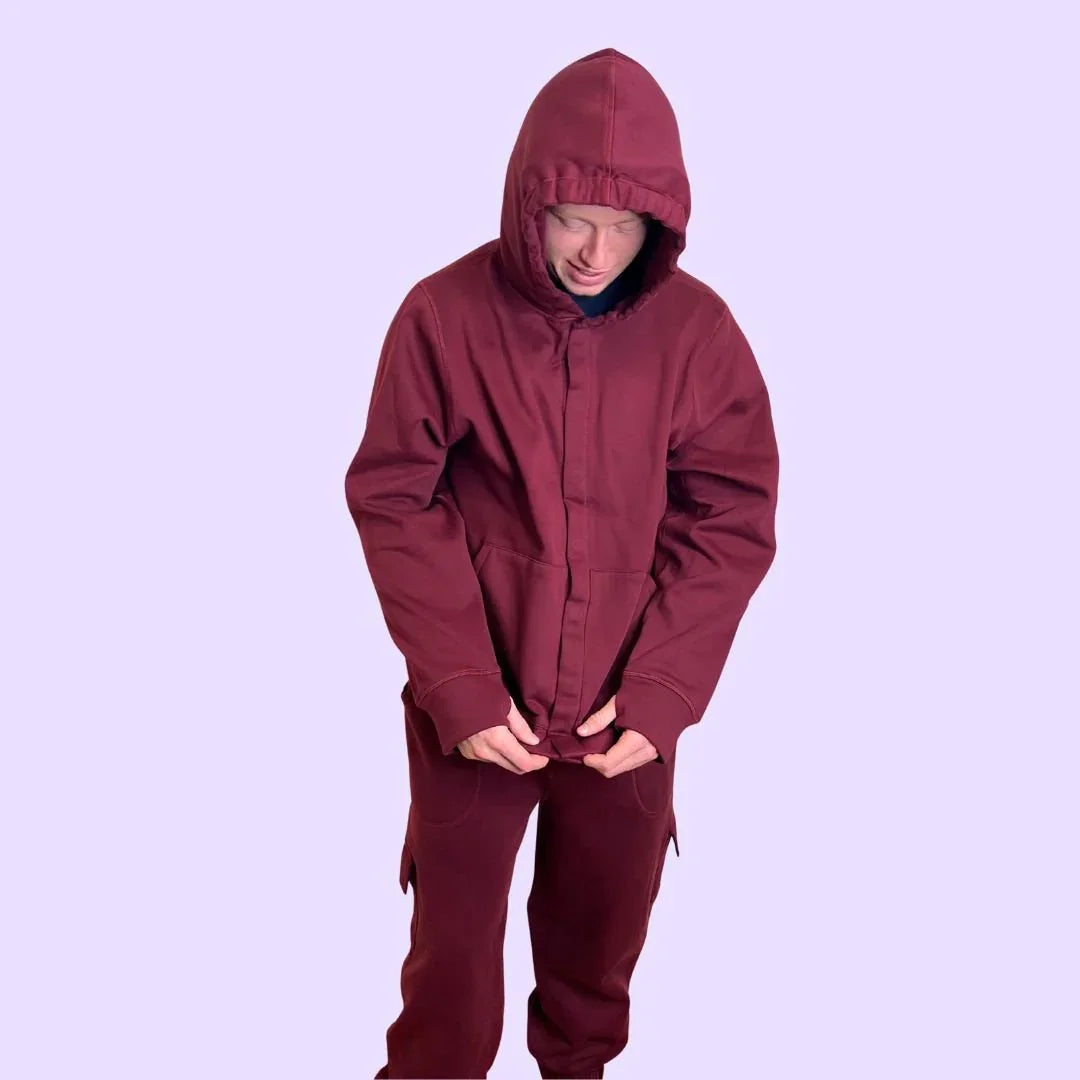 Person wearing sensory-friendly maroon hoodie and pants set on lavender background