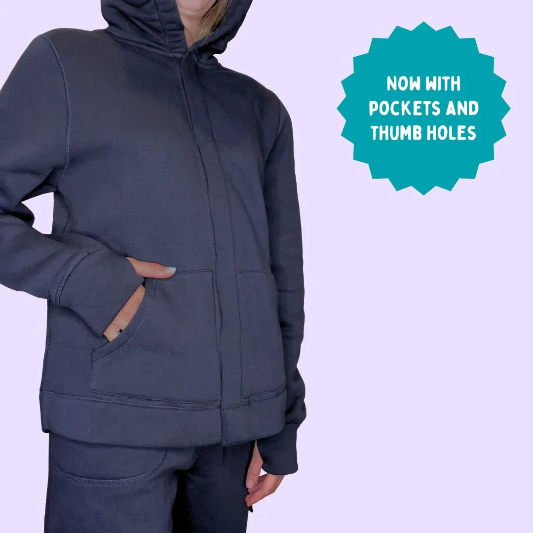 Sensory-friendly zip-up hoodie with pockets and thumb holes, modeled on pastel background.