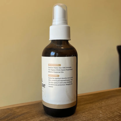 Natural bug spray bottle with essential oils and ingredient label on wooden surface