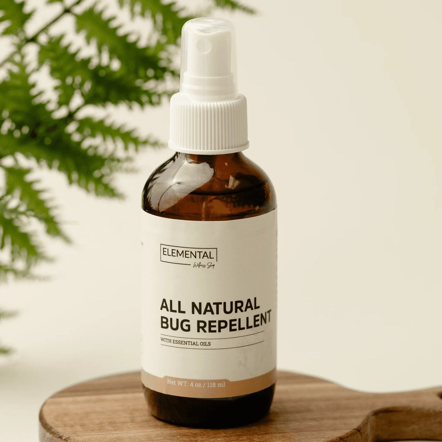 All-natural bug repellent spray with essential oils in amber bottle on wooden tray