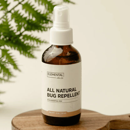 All-natural bug repellent spray with essential oils in amber bottle on wooden tray