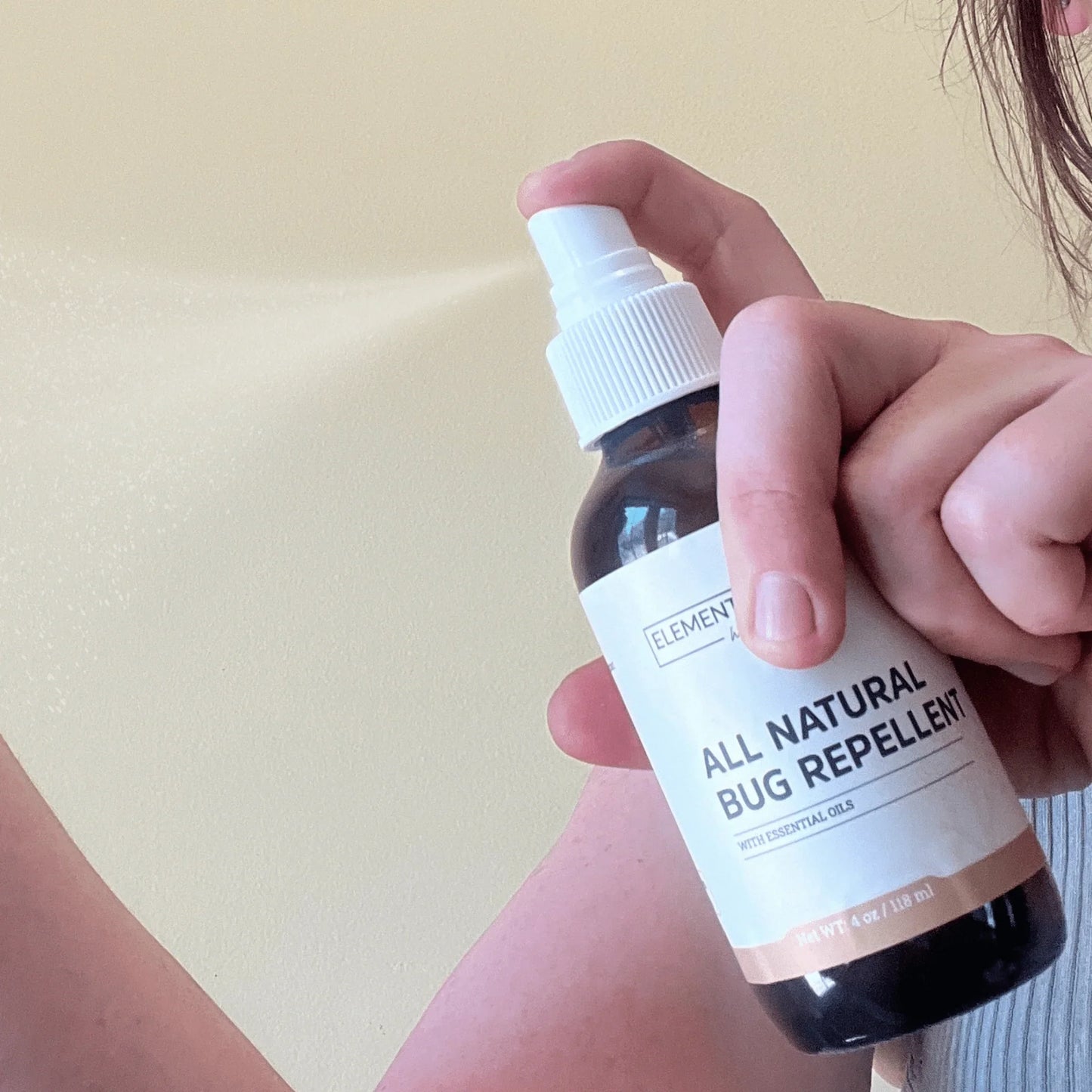 Person spraying all natural bug repellent with essential oils onto skin