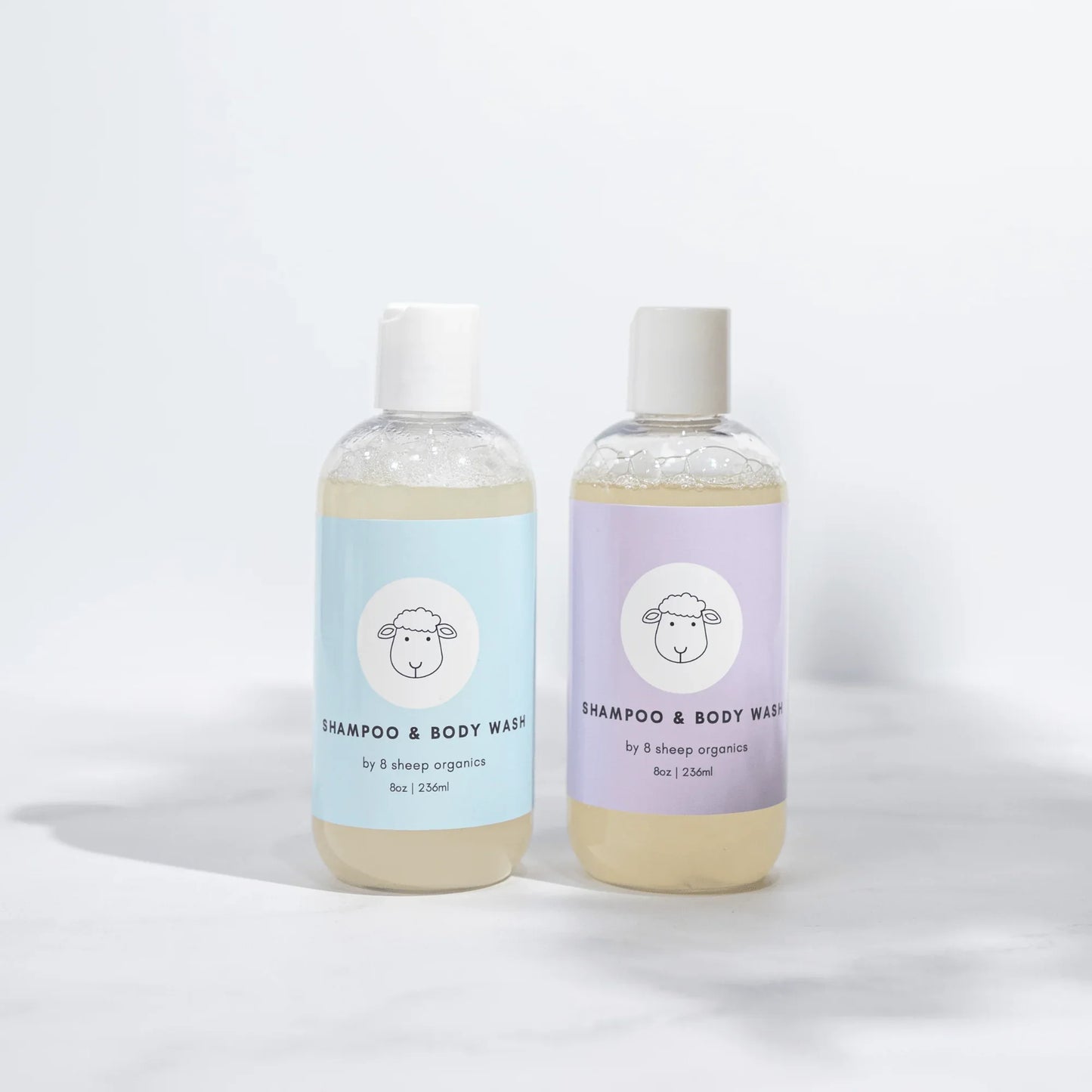 Two bottles of 8 Sheep Organics shampoo and body wash with pastel blue and purple labels.