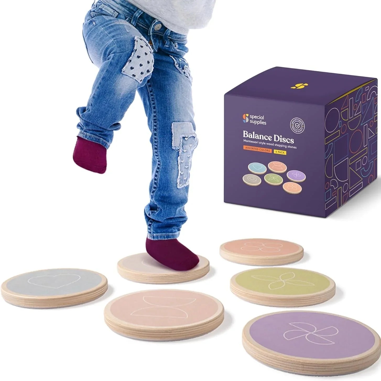 Child stepping on pastel wooden balance discs for sensory play and motor skills with product box.