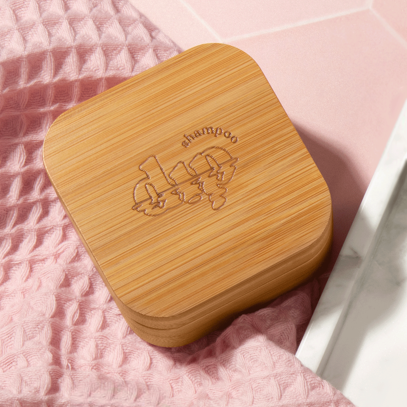 Wooden shampoo and conditioner box with engraved design on a pink textured surface
