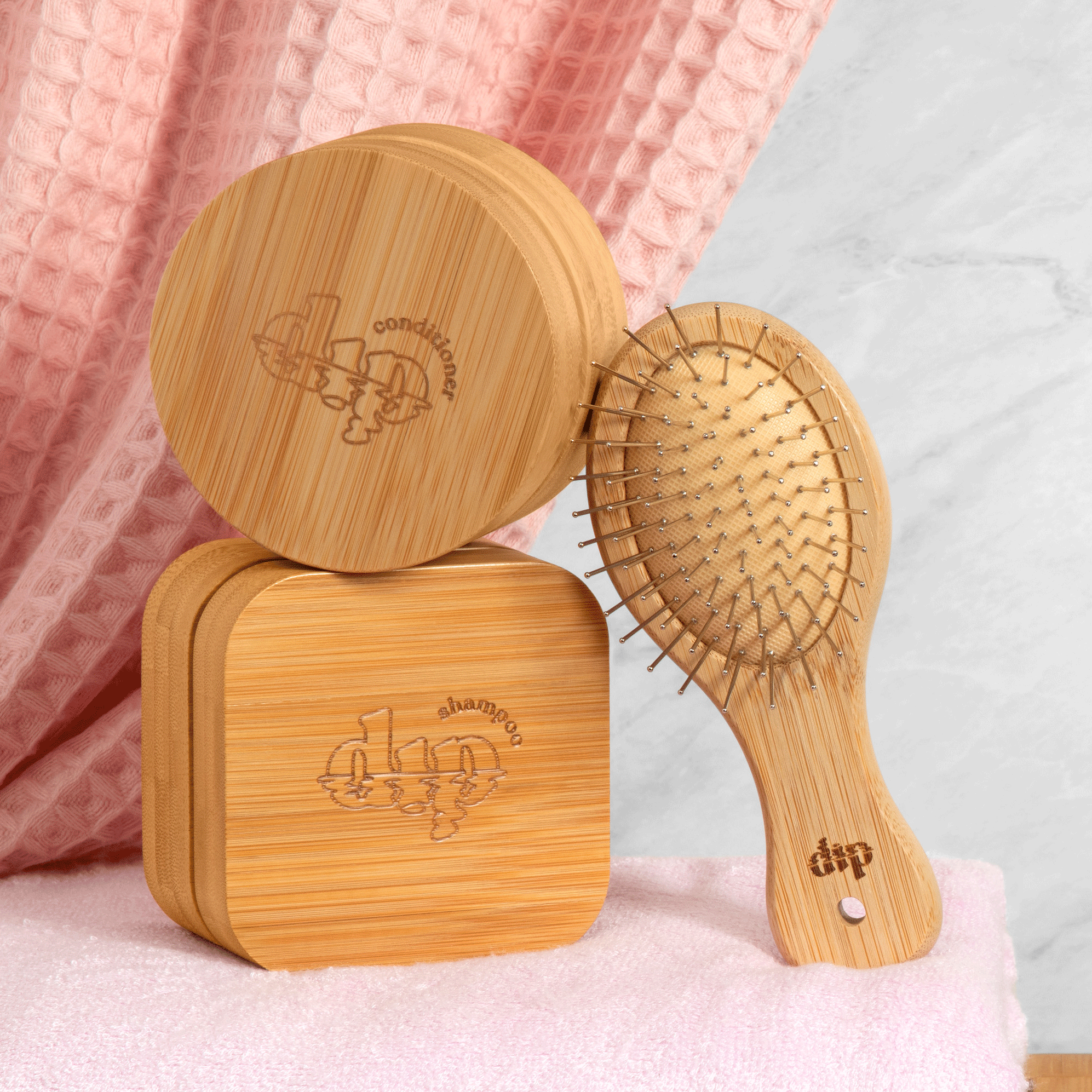 Wooden hairbrush and its packaging on a pink surface with a light gray background