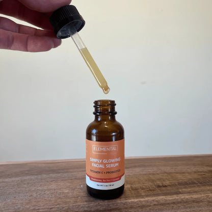 Dropper applying Simply Glowing facial serum with vitamin C and probiotics in amber bottle