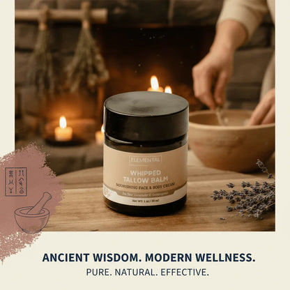 Elemental whipped tallow balm jar on table with lavender, candles, and cozy fireplace background