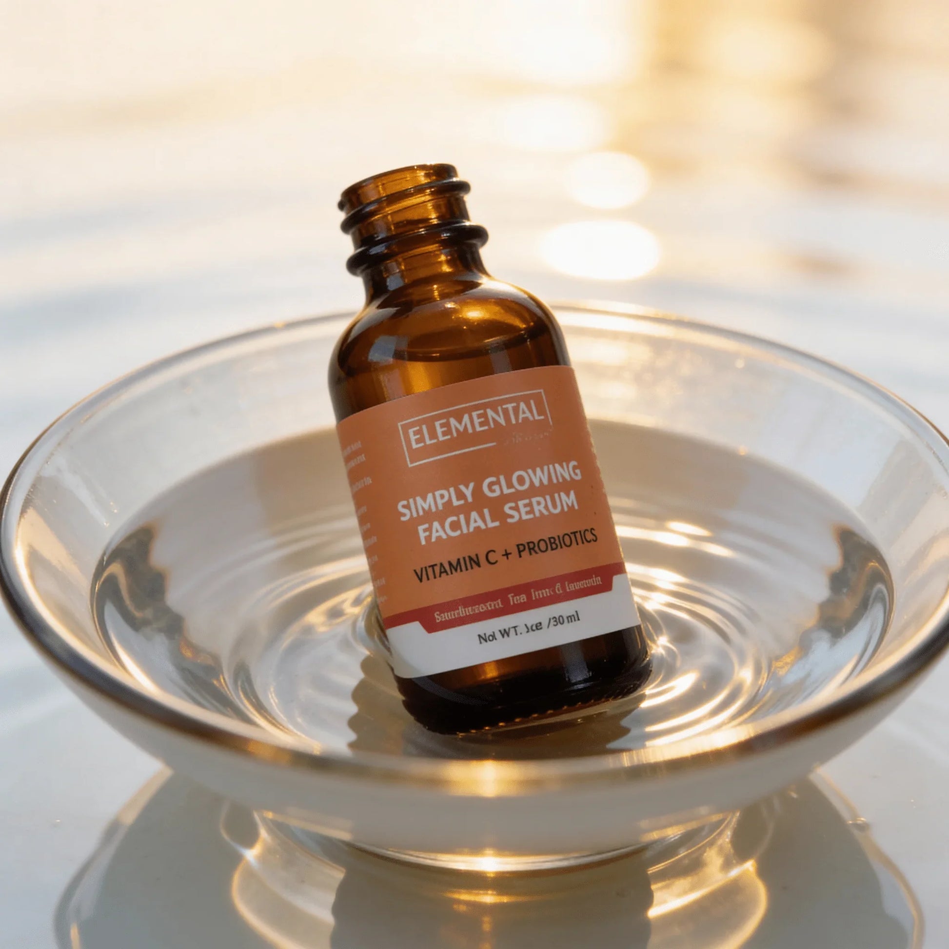 Vitamin C probiotic facial serum bottle in glass bowl with water and golden sunlight