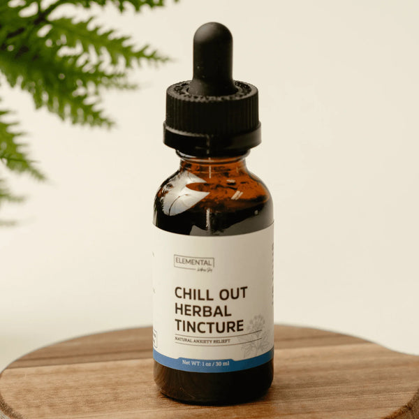 Chill Out herbal extract dropper bottle resting upright on a rustic wood tabletop surface.