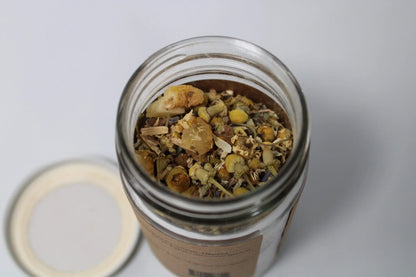 Glass jar filled with loose leaf herbal tea blend featuring chamomile and dried herbs