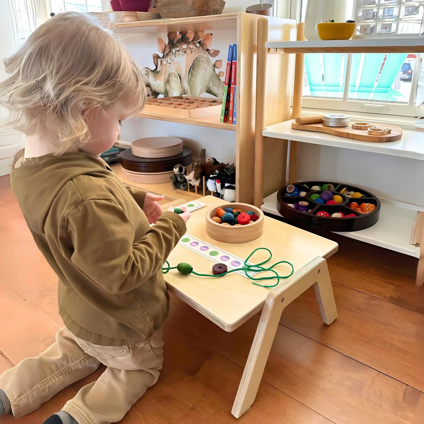Child playing at a Montessori workspace with sensory-friendly learning toys on a wooden table.