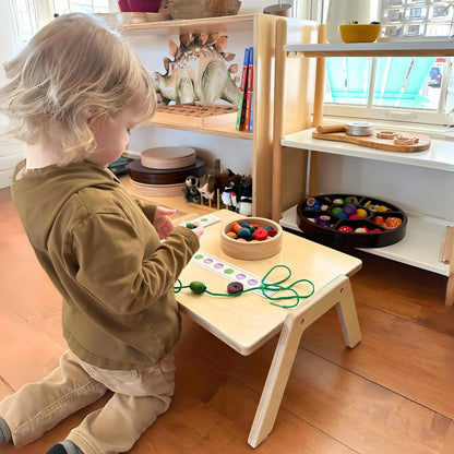 Child playing at a Montessori workspace with sensory-friendly learning toys on a wooden table.