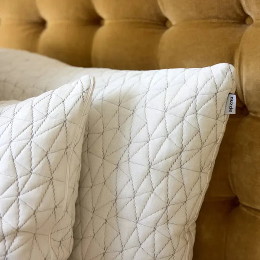 Quilted sensory-friendly cream pillows on a tufted bed headboard