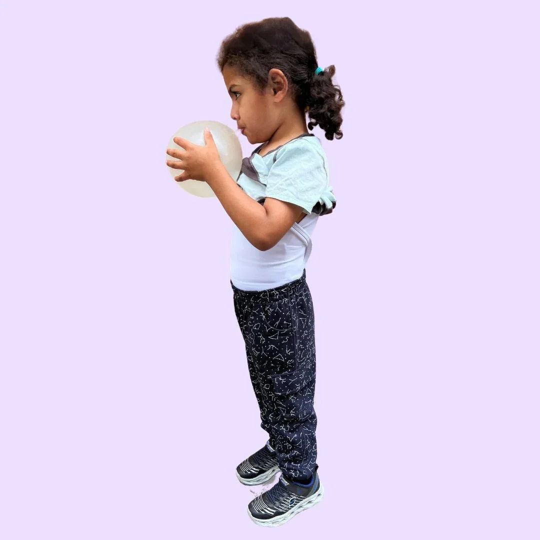 Child wearing sensory compression shirt and cosmic print pants holding a sensory ball