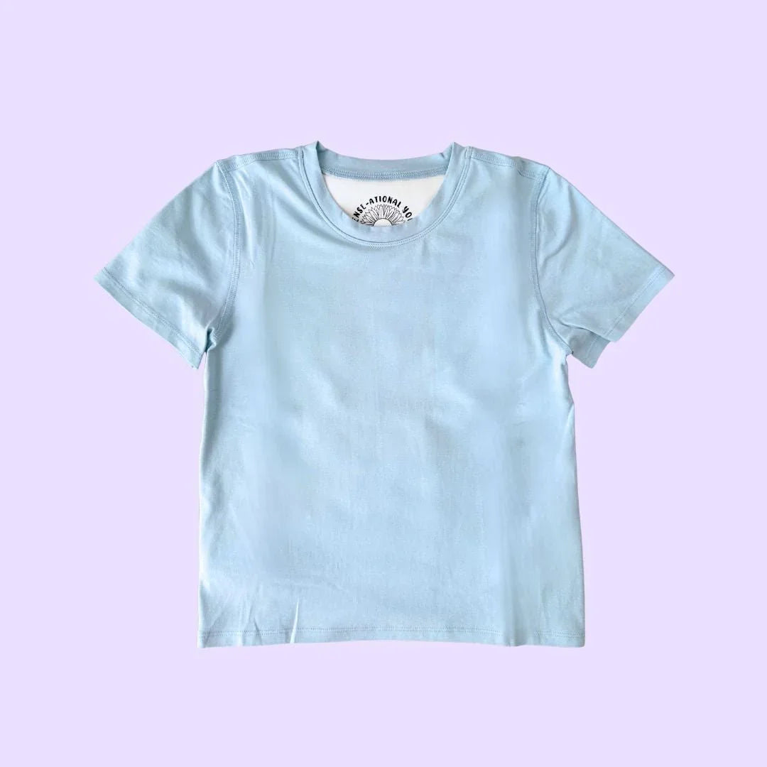 Light blue kids compression sensory shirt with short sleeves on a purple background
