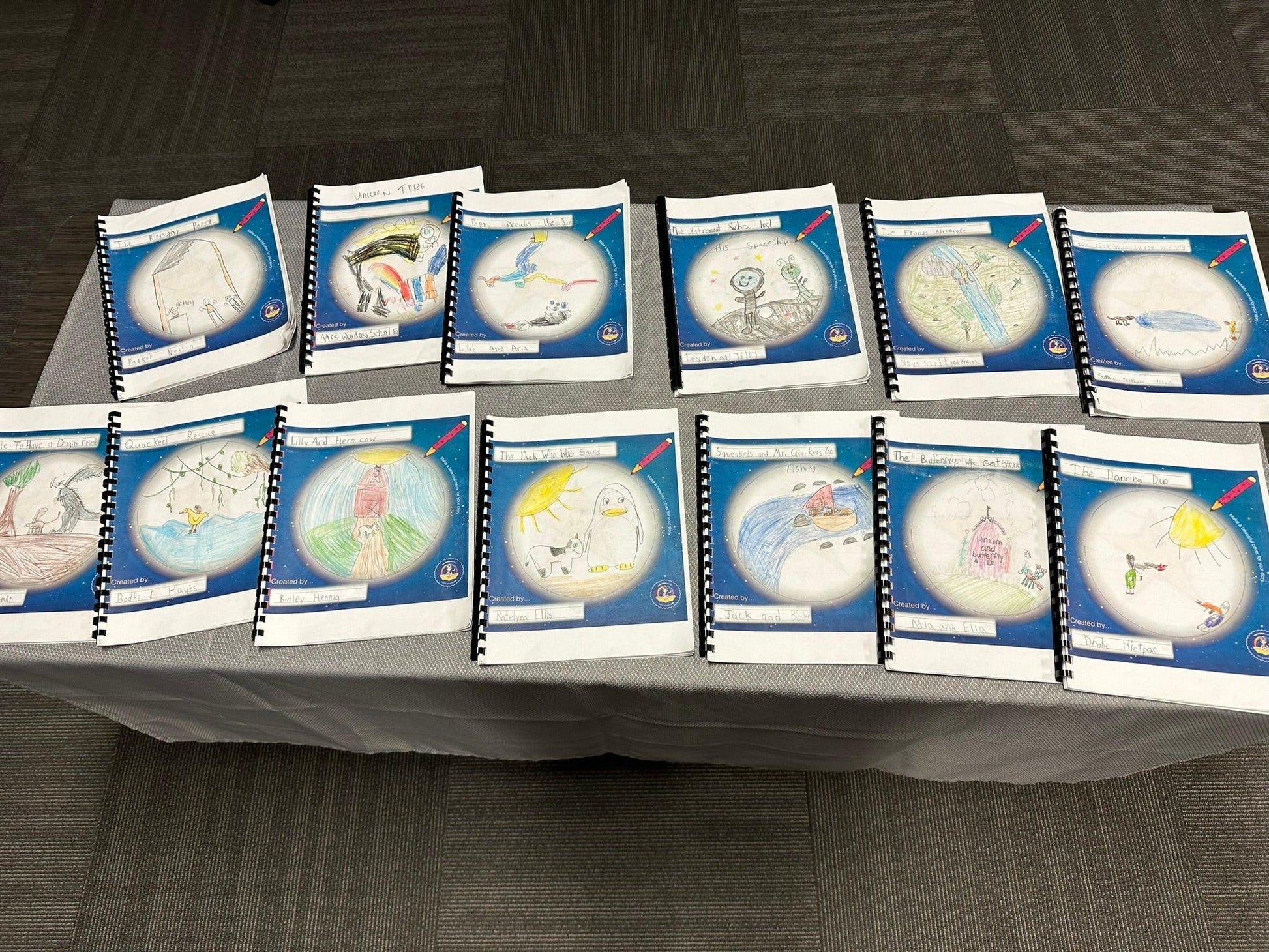 Children's illustrated storybooks with spiral bindings displayed on a table, featuring colorful hand-drawn covers.