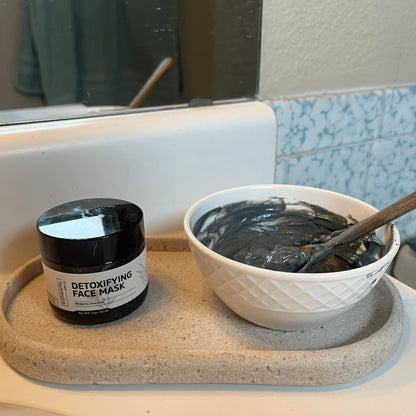 Detoxifying face mask jar and mixed clay mask in a bowl on bathroom counter