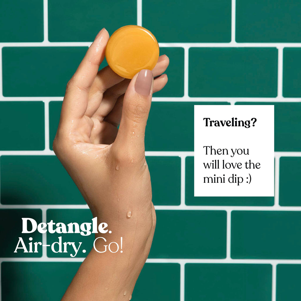 Hand holding a small round object with text on a green tiled background