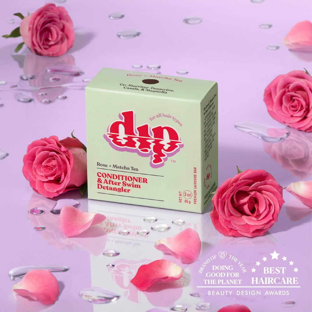 Box of 'dip' conditioner with pink roses and rose petals on a purple background