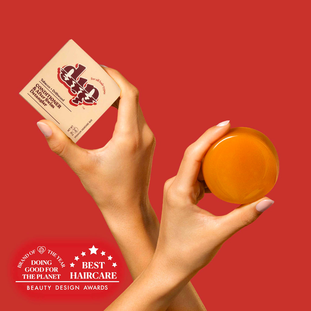 Hands holding a jar of hair product and a box against a red background with awards text.