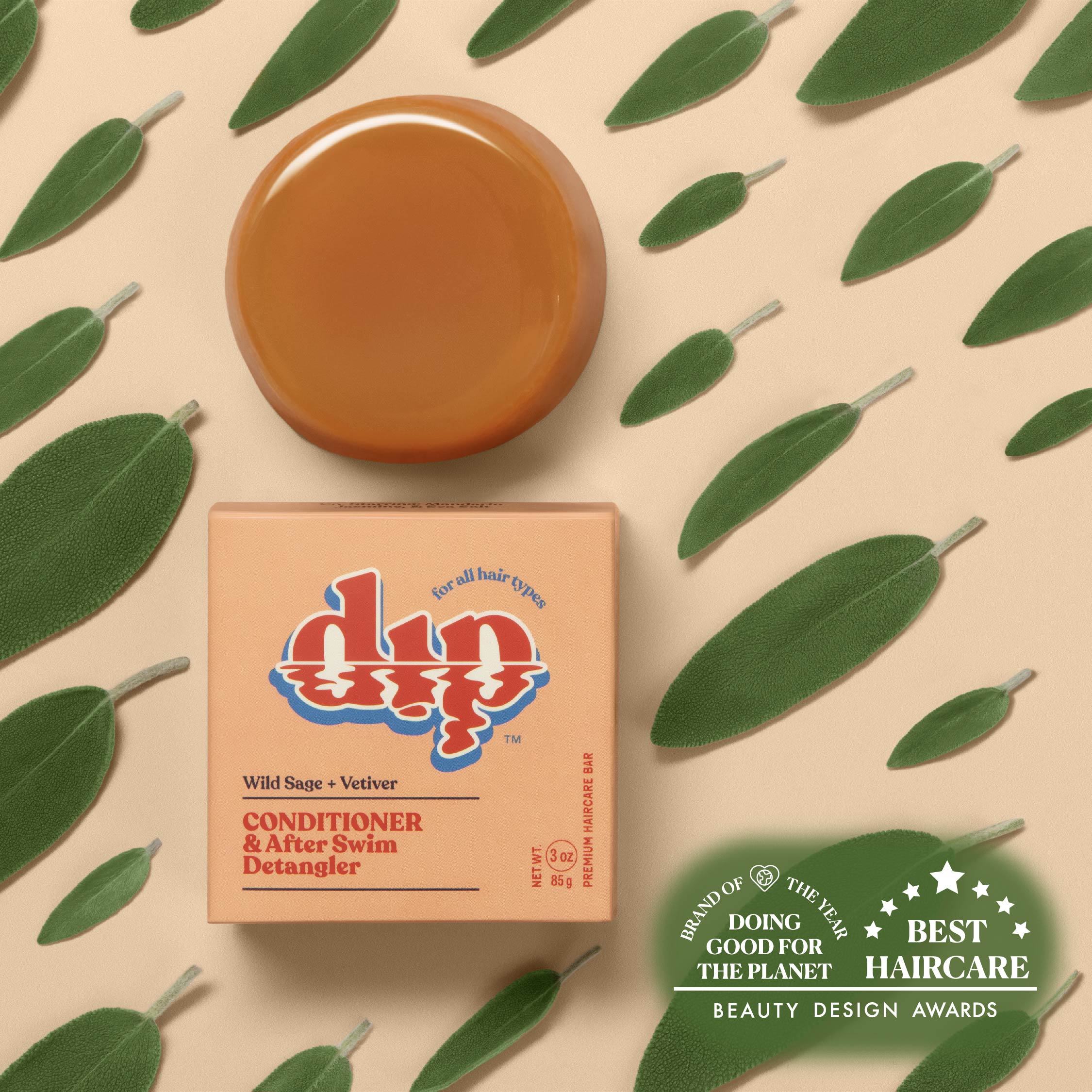 DyP conditioner bar with packaging on a beige background with green leaves
