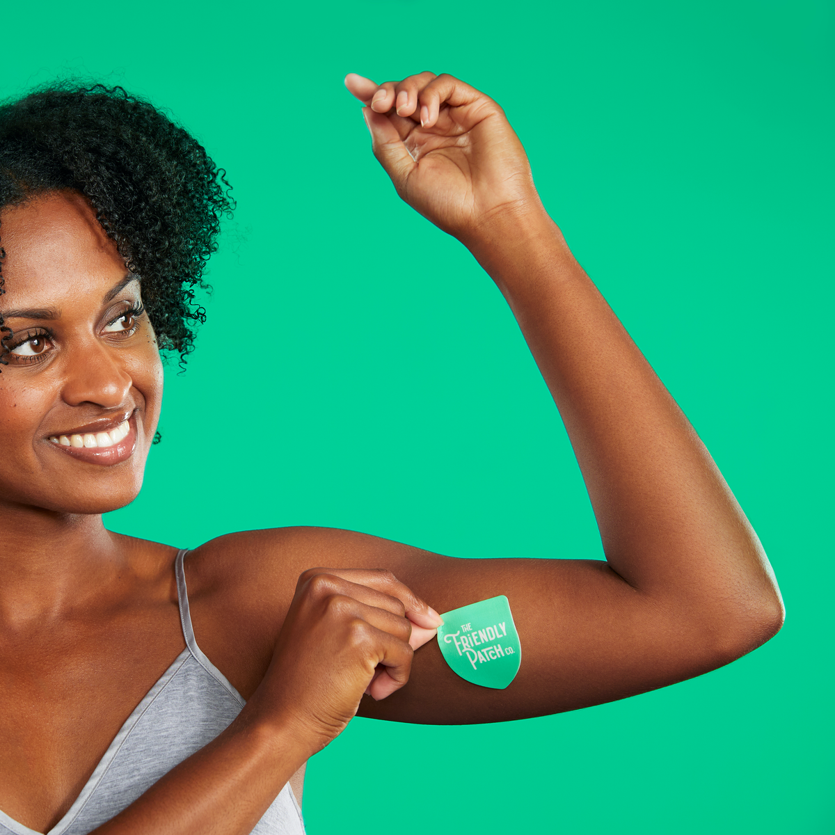 Woman showing a green patch on her arm against a green background