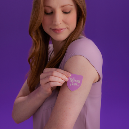 Woman applying a purple patch with text on her arm against a purple background