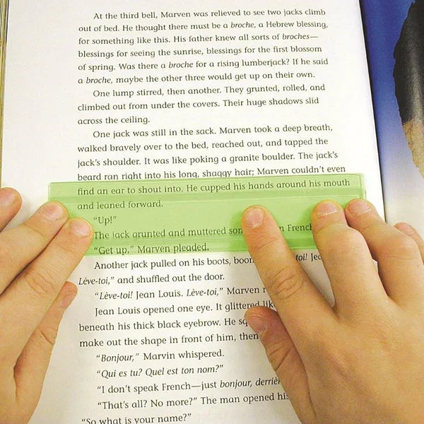 Hands using a green reading guide strip over a book page, aids focus and reading comprehension