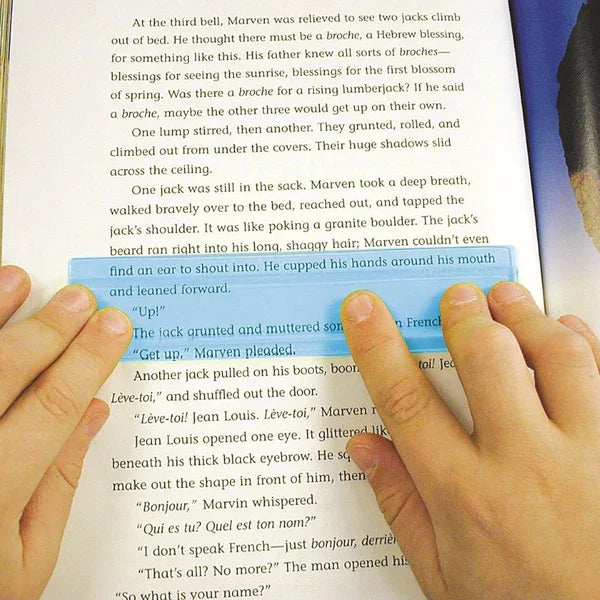 Hands using a blue reading strip to highlight text in a book, learning aid for dyslexia