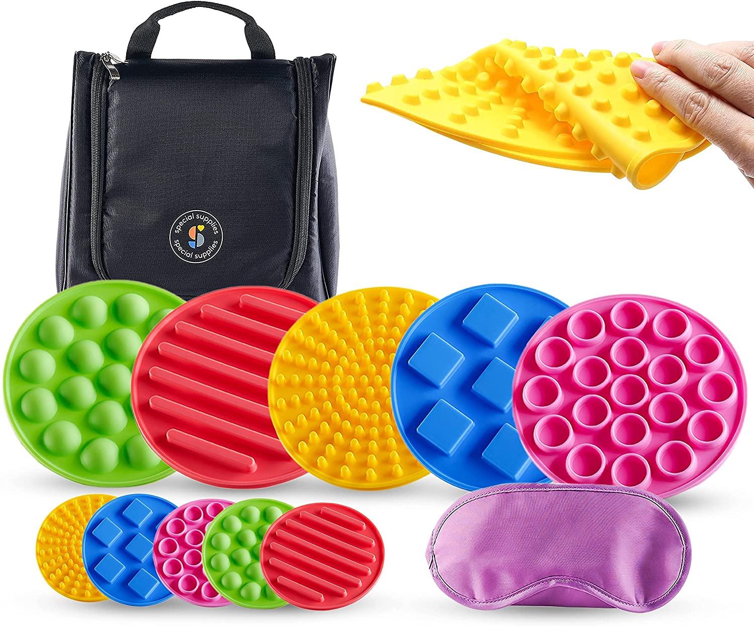 Colorful sensory tactile discs set with various textures, eye mask, carrying bag, and hand pressing yellow disc.