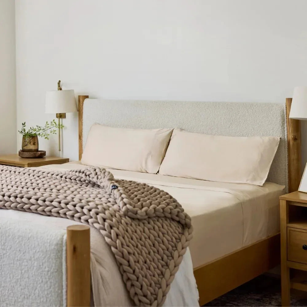 Beige chunky knit cooling weighted blanket on a neatly made bed in a cozy bedroom.