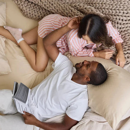 Couple relaxing on bed with chunky knit cooling weighted blanket in beige