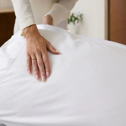 Hand smoothing a white cooling weighted blanket on a bed for sensory-friendly comfort
