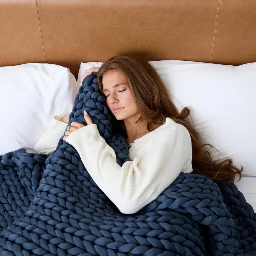 Woman relaxing in bed with a chunky knit weighted blanket, sensory-friendly for sleep support