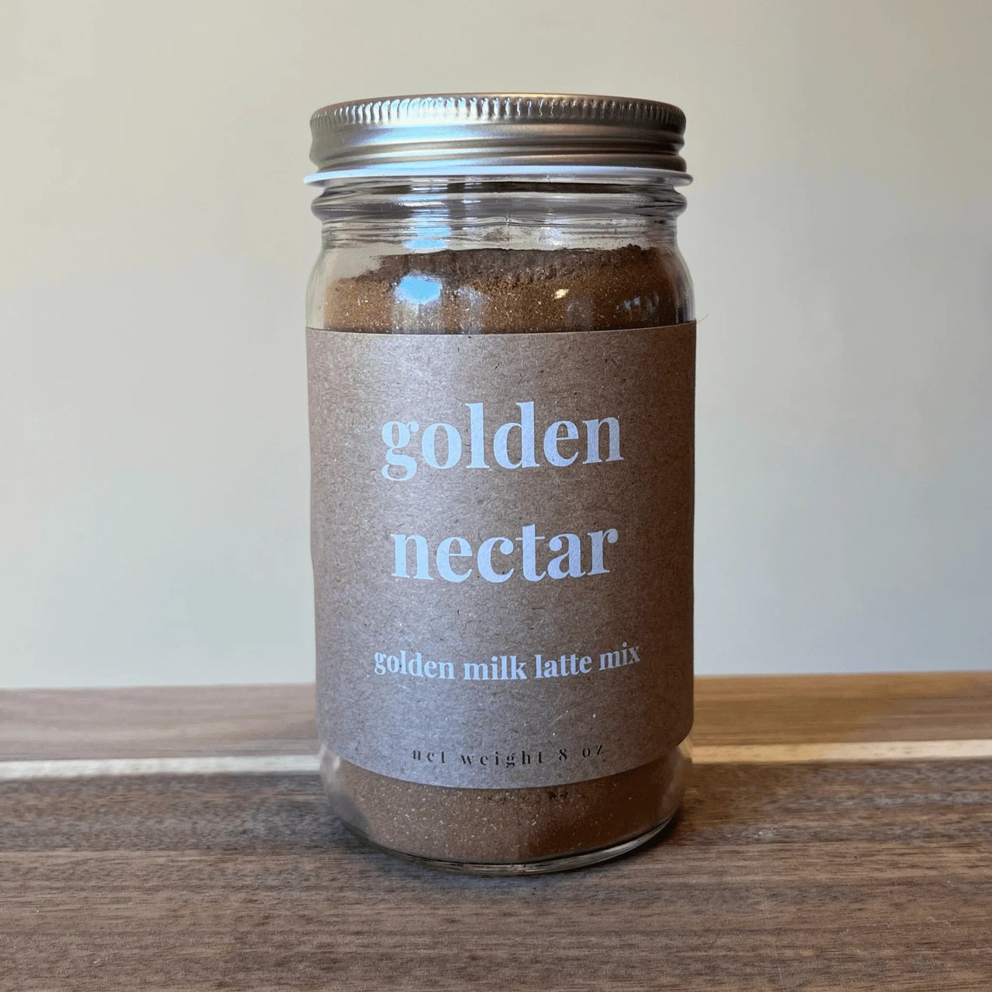 Golden Nectar golden milk latte mix in glass jar with brown label on wooden surface