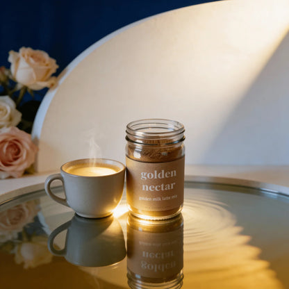 Golden milk latte mix jar and steaming latte on reflective surface with roses in background