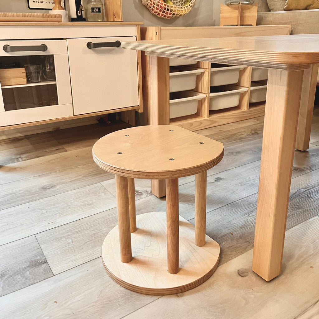 Wooden stool in a kitchen setting with a table and cabinets.