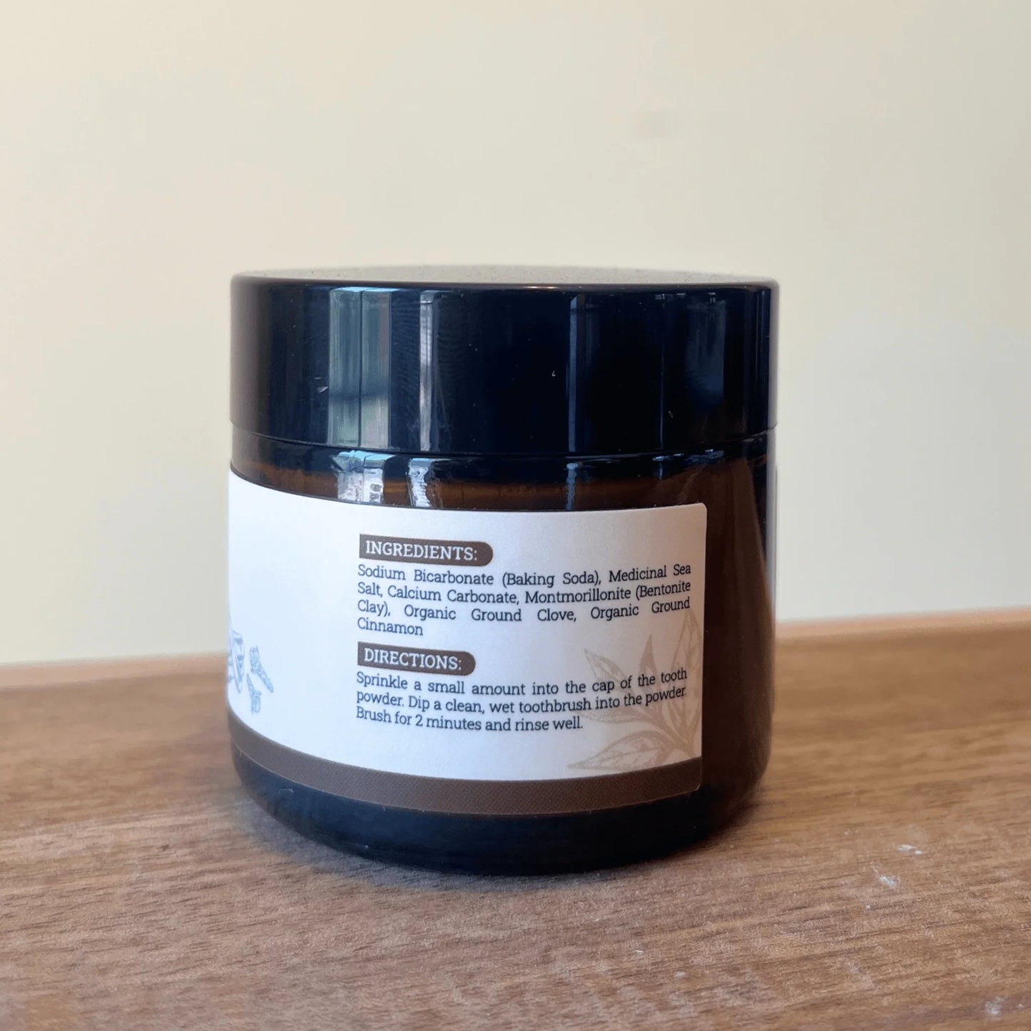 Natural remineralizing tooth powder jar with ingredient and usage label on wooden surface