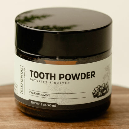 Charcoal and mint tooth powder jar, detoxifying and whitening, on wooden surface