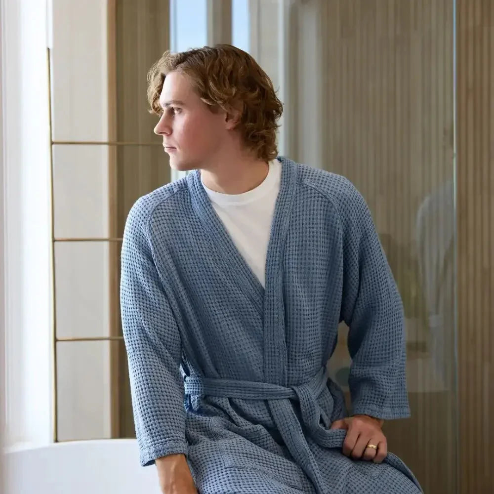 Man wearing a sensory-friendly blue waffle robe sitting by a window