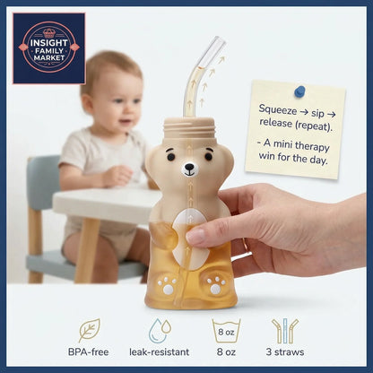 Bear-shaped drink container with straw held by a hand, child sitting at a table in the background.